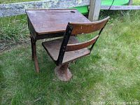 Photo showing the antique schoolhouse desk with attached wooden chair, detailed view of the steel base, wood seat, and desk surface.