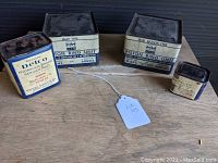 Photo shows all four vintage GM car parts with original sealed packaging, laid out on a wood surface.