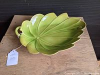 Photo showing top side of the green leaf-shaped ceramic serving platter with handle.