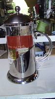 Full side view of French press showing transparent glass and stainless steel handle and base.