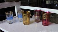 Five assorted mid-century juice tumblers on white surface, showing color and decorative patterns