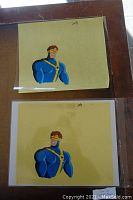 Two original Cyclops animation cells showing his upper body on yellow background sheets.