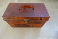 Front angled view of amber colored see-through rectangular sewing box with lid and handle visible