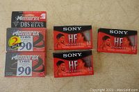 Photo shows two unopened Memorex DBS Normal Bias 90-minute cassette tapes (one 2-pack, one single) and three unopened Sony HF High Fidelity 60-minute cassette tapes arranged on a flat surface.