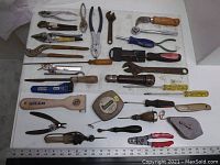 Overview of all assorted antique hand tools laid out on a white surface, showing variety in tool types, handles, and conditions.