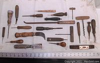 Full set of assorted hand tools laid on a cloth, showing a variety of woodworking and gardening tools with wooden handles and metal parts.