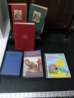Photo showing nine assorted children’s books with varied colored covers including red, blue, green, maroon. Titles visible include Heidi, Big Bird, Jubilee Books.