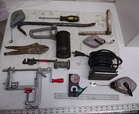 Photo showing assorted hand and measuring tools on a white surface with a ruler at the bottom for size reference.