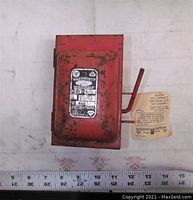 Closed Wadsworth fire alarm pull station showing front plate with label and rust spots with attached instruction tag.