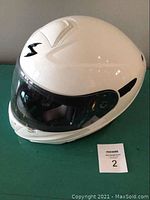 Front and slight right angle view showing off the glossy white helmet surface, clear visor and drop-down tinted internal sun visor.