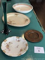 Overview of all five items arranged on a green surface: blue glass vase, small floral china plate, metal dish, Burleigh oval plate, large floral china dish.