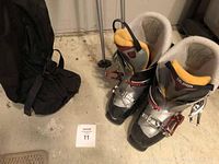 Salomon ski boots, black travel bag, partially visible ski poles