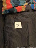 Sleeping bag opened showing reversible solid brown side and camouflage pattern side tabs.