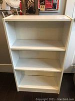 Front view of the white bookshelf showing three shelves, one shelf is adjustable.