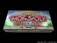 Game box with Monopoly Deluxe Edition branding and iconic Mr. Monopoly character on top illustrated with the Monopoly board design around the edges.