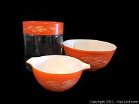 Group photo of the three Pyrex Autumn Harvest Wheat items: the orange glass canister with lid, and two bowls including the smaller Cinderella bowl with spouts and the larger round bowl.