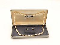 Full view of the pearl necklace and matching stud earrings in the original Vista grey hard case with velvet lining and Vista logo on the lid.