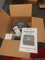 Opened box showing Latham Model 800P time clock unit and User's Guide booklet inside the packaging box.