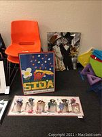 Children's wall art displayed on floor including puppy puzzle, colorful childrens dress-up print, and framed educational poster