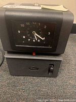 Front view of the Latham Time Clock model 2121 showing the clock face with analog hands and red card indicator, sitting on the card slot base with the Latham logo.