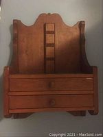 Front view of the wooden stationary shelf showing two drawers with round knobs and decorative top edge.
