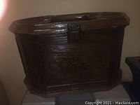 Closed exterior view of vintage plastic sewing box showing octagonal shape, latch, and faux wood grain texture.