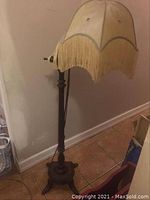 Full view of the antique wooden bridge floor lamp showing base, stand, and fringed fabric shade.