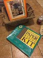 Woven basket with Paper Making Kit and other craft supplies on tile floor