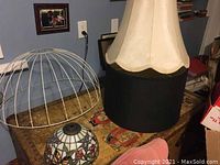 Four lampshades shown including a beige fabric shade with water stains, a black fabric shade, a white wire frame shade with broken top, and a stained glass dome shade.