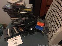 A pile of miscellaneous cassette tapes in various open and closed cases scattered on a lace chair and table surface.