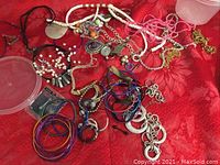 Overview showing assorted necklaces, bangles, earrings, and accessories laid on red fabric.