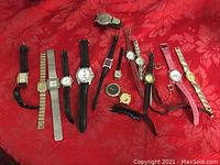 Wide shot showing all watches laid out on a red fabric background