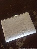 Closed view of the white embossed leather wallet showing overall texture and shape.