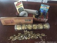 Overview of lot showing obsidian figure, gold-colored spherical ornaments, metal floral decorations, small ceramic bowl, vintage air freshener, and Pez dispensers.