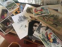 Various unframed prints laid out showing roosters, castle, Bob Marley, and others