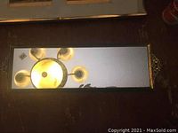 Top view of rectangular mirror tray showing reflective surface and gold-tone cherub handle at one end.