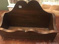 Front view of solid wood shelf or box showing the double arch back and scalloped front edge.