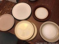 Top view of five assorted Denby plates showing varied colors and styles all in used condition.