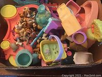 Photo showing multiple Littlest Pet Shop animal figures, including dogs and others, with playset accessories such as pet beds, strollers, and other colorful plastic pieces in a box.