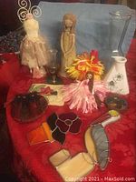 Full lot with stained glass pieces, vases, figurines, and flowers arranged on red fabric.