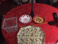Overview photo showing vintage rose tray, white ceramic rose dish, painted round floral dish, small square container, long wooden pipe, and black vase on a red tablecloth