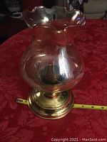 Brass hurricane candle holder upright showing polished brass base and clear etched glass shade with ruffled top.