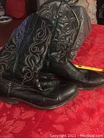 Side view showing black leather, embroidered patterns, and heel shape