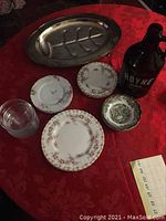 Overview of all items including metal roast tray, various decorative plates, glass bowls, and large glass jug.