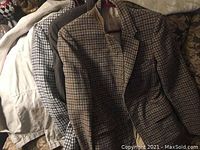 Four men's jackets hanging side by side showing fabric patterns and colors.