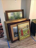 Three framed artworks leaning against wall