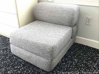 Gray upholstered folding chair in upright position with cushioned backrest and seat.