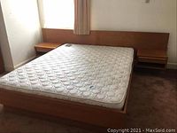 Assembled bed frame with mattress displayed (mattress not included) showing integrated headboard and side nightstands.