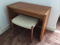 Wooden vanity table with bench underneath showing front and side view, table has discoloration marks on the top.