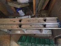 Top view of the aluminum extension ladder showing the hollow rails and metal rungs, with visible scratches and dirt.